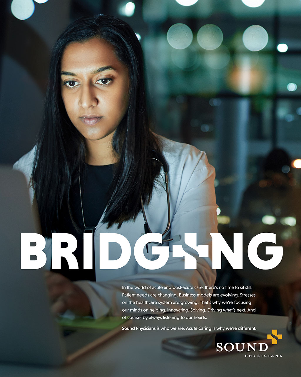 A focused woman in a lab coat working on a laptop in a modern office environment, with the word "BRIDGING" prominently displayed. The background features soft lighting and a professional atmosphere, highlighting her concentration and commitment to her work.
