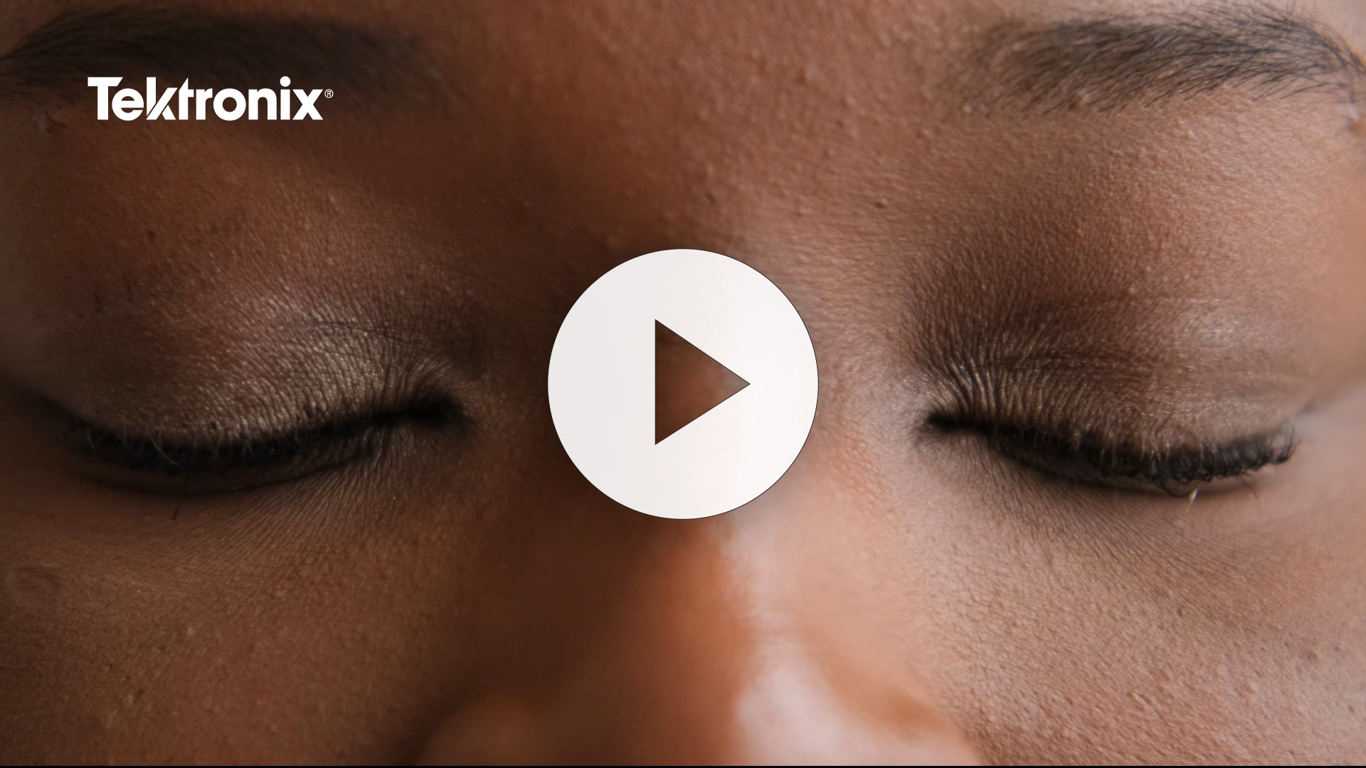 Close-up image of a person's closed eyes with subtle makeup, featuring the Tektronix logo and a play button overlay, indicating a video presentation related to the brand.