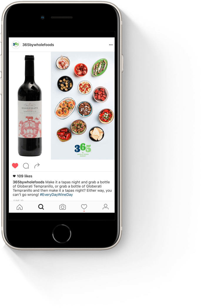 A smartphone displaying an Instagram post featuring a bottle of red wine alongside a variety of colorful appetizers, showcasing a vibrant food and drink pairing.
