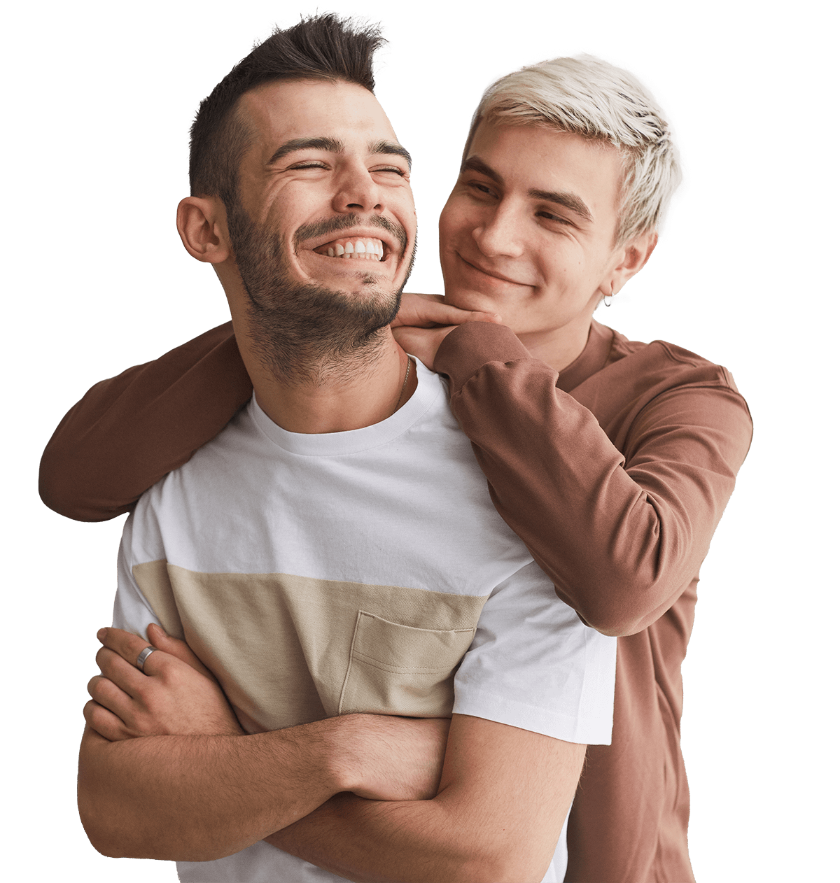 Two young men share a joyful moment, with one embracing the other from behind. They are smiling and exuding happiness, showcasing a close friendship or romantic relationship. The background is plain, emphasizing their expressions and connection.