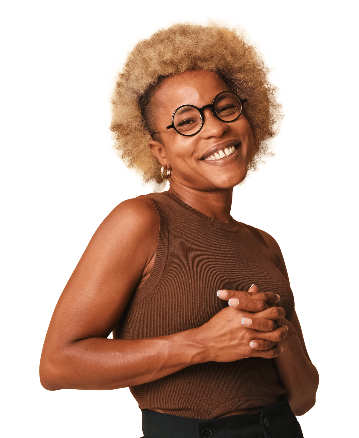 Smiling woman with curly blonde hair and glasses, wearing a brown sleeveless top, poses with hands clasped. The image conveys confidence and positivity, suitable for lifestyle or fashion content.