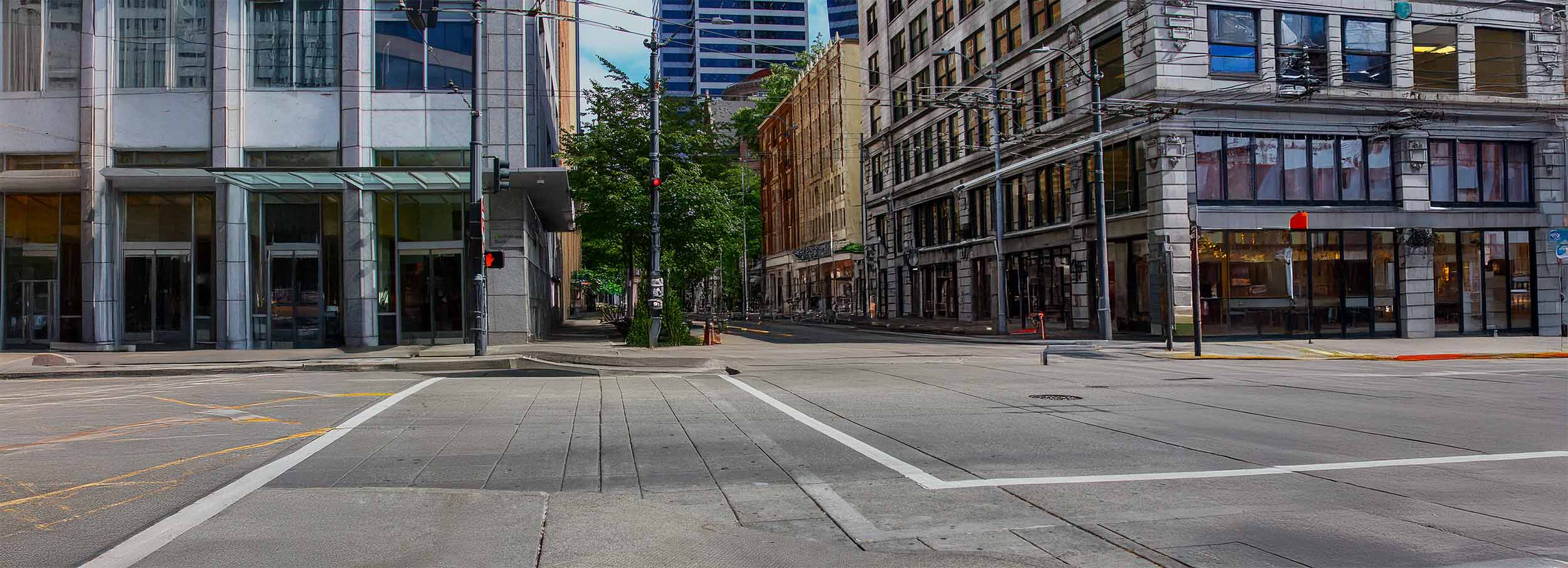 Urban street view showcasing a mix of modern and historic architecture, with tall buildings and trees lining the sidewalks in a vibrant city setting.